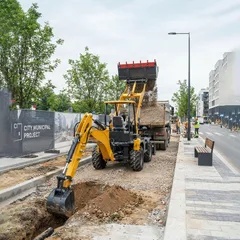 Mini backhoe loader excavating soil on a residential construction site